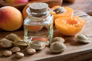 A bottle of apricot kernel oil with apricot kernels and apricots